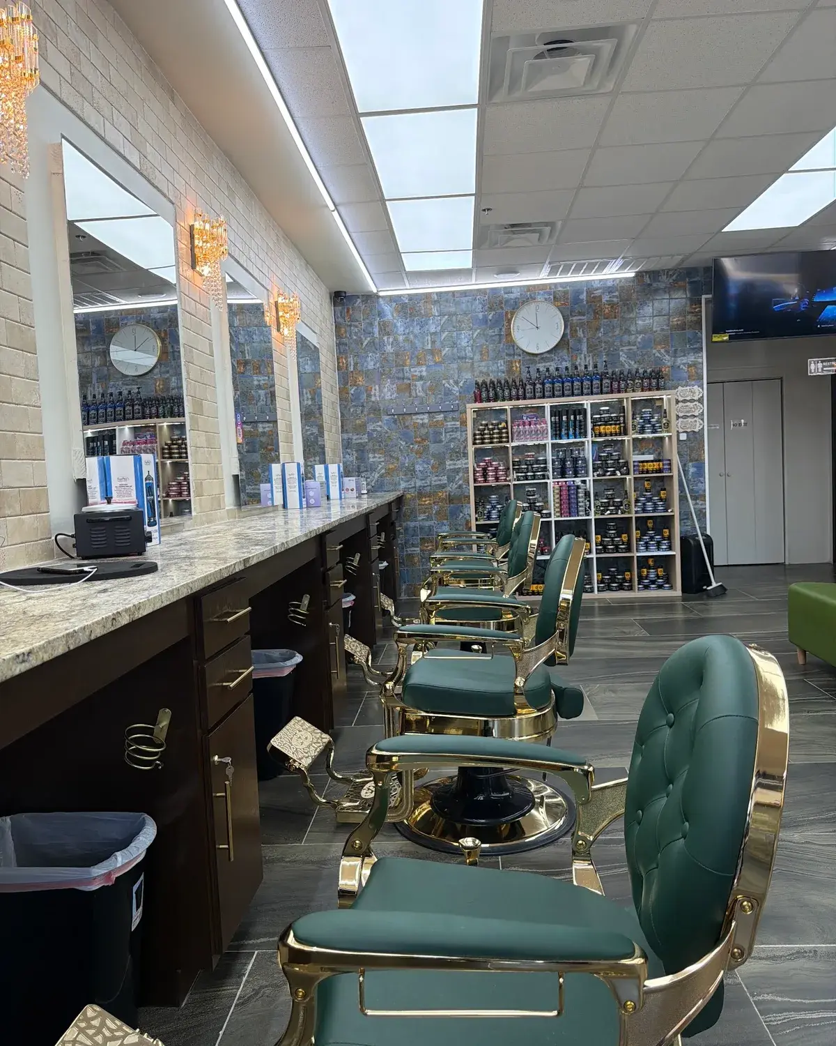 A row of green and gold barber chairs along the mirrors