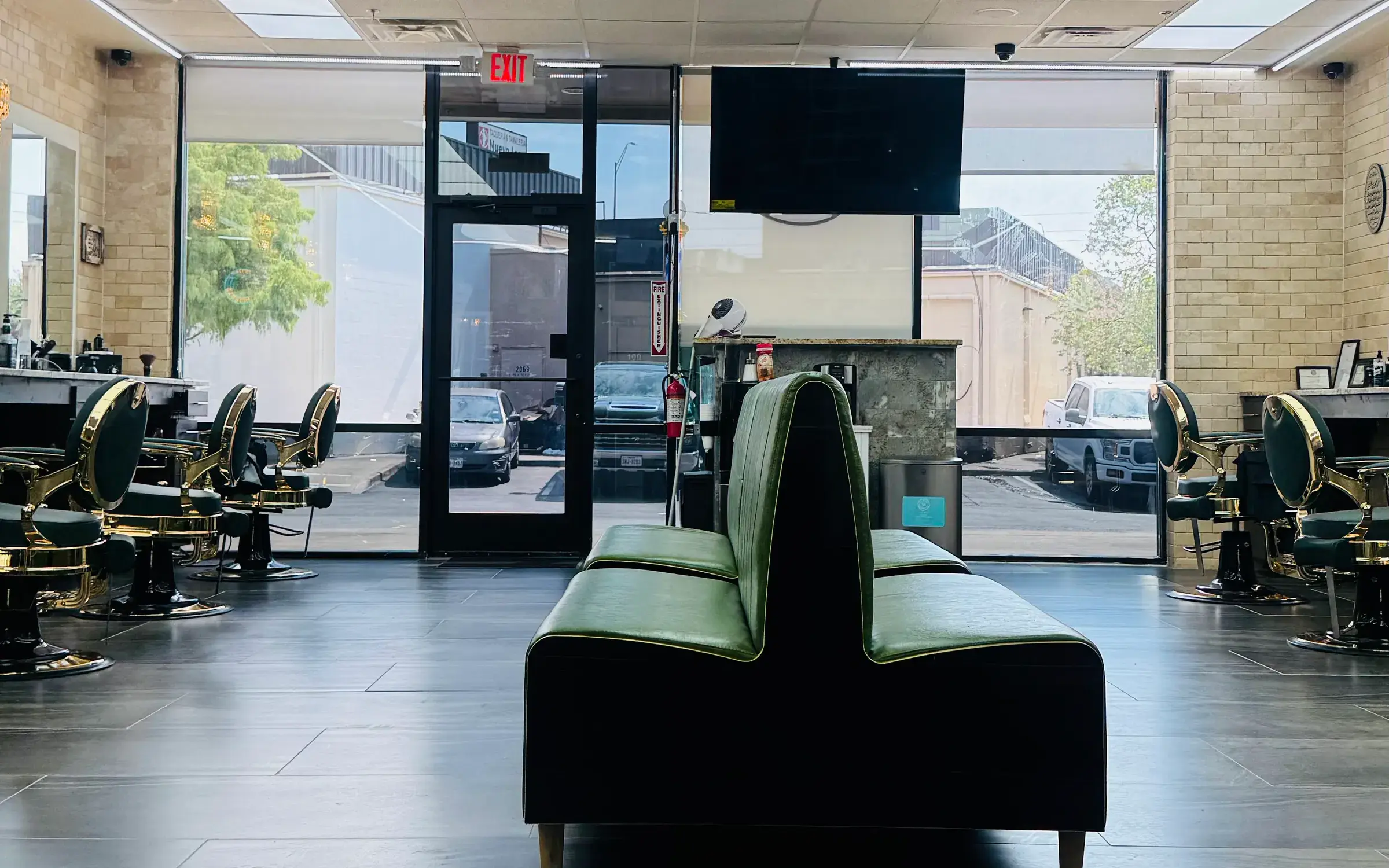 Inside KP's Barber Shop: green leather barber chairs with gold frames along both walls and a green waiting bench