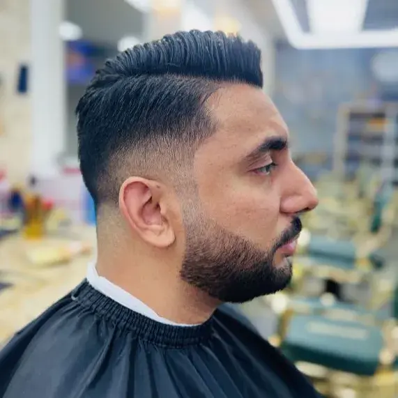 Comb over with a low fade and a full, lined-up beard