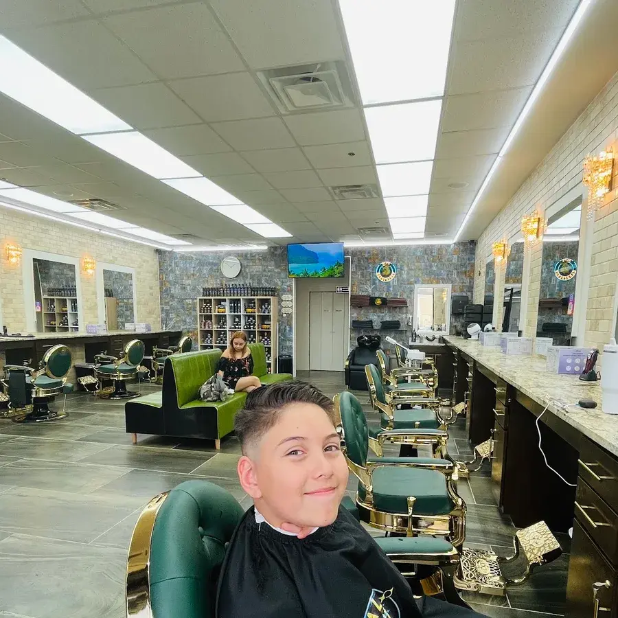 A boy smiling in a green barber chair after his haircut