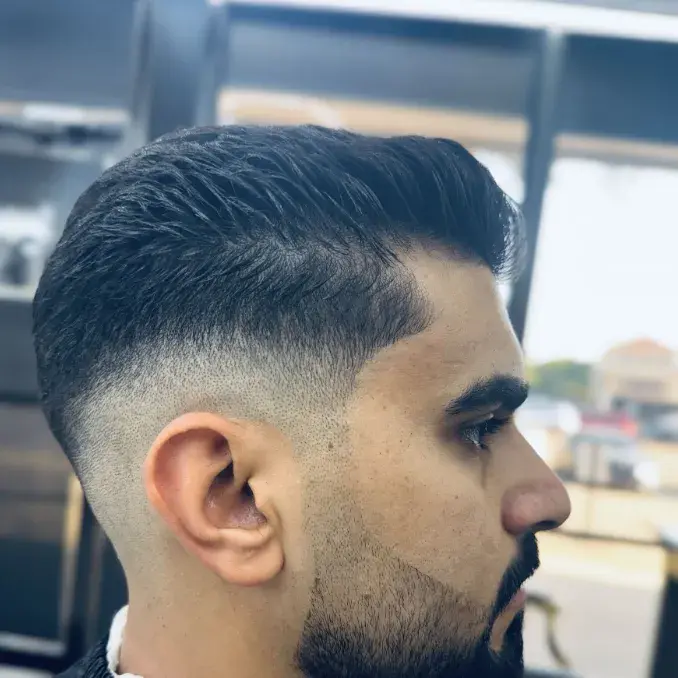 Mid skin fade with a swept top and a lined-up beard